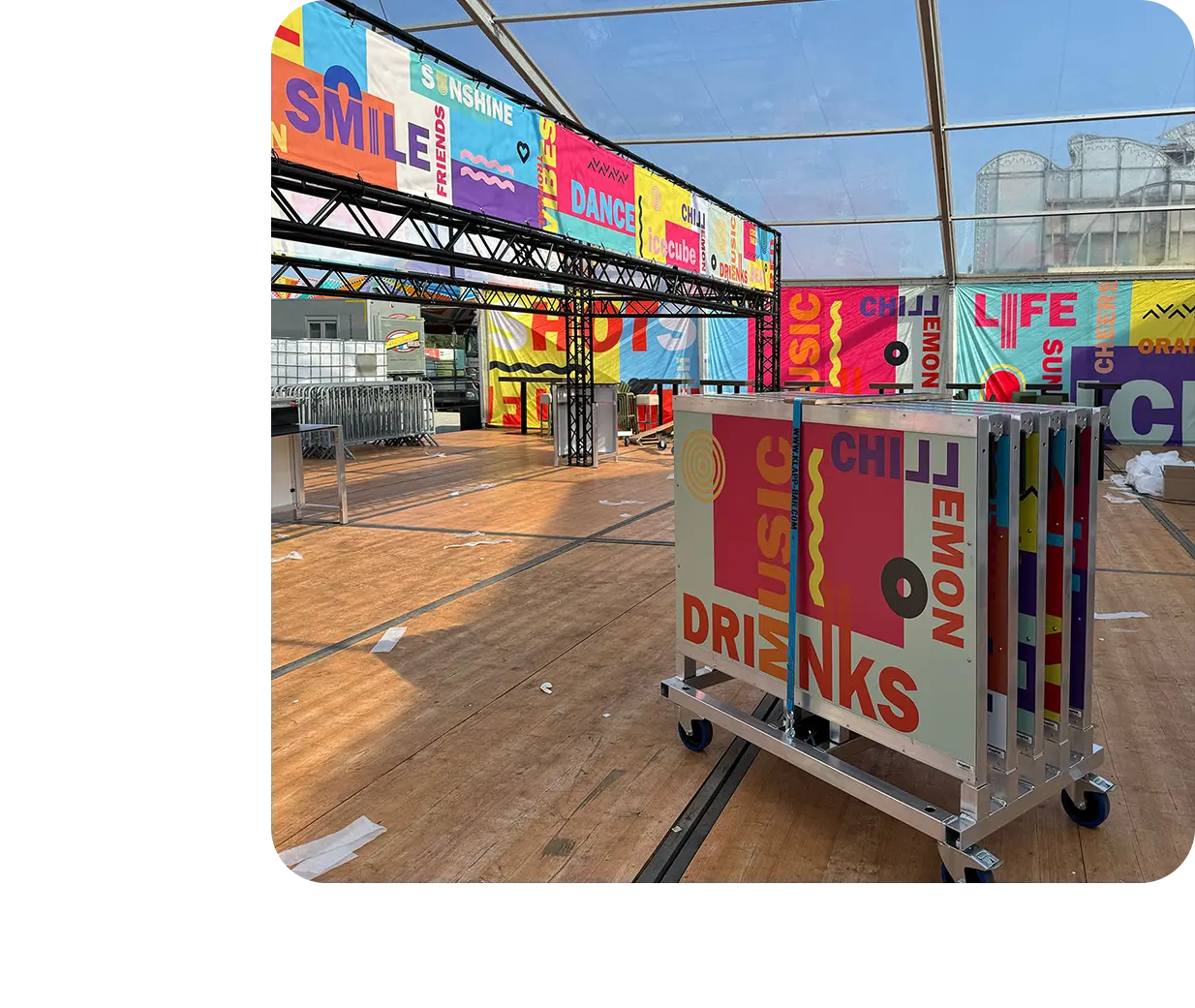 Farblich gebrandete klappBAR 1.5 auf einem Transportwagen, im Inneren eines Festivalzelts mit Beschilderung für Musik, Drinks und Chill-Zonen.